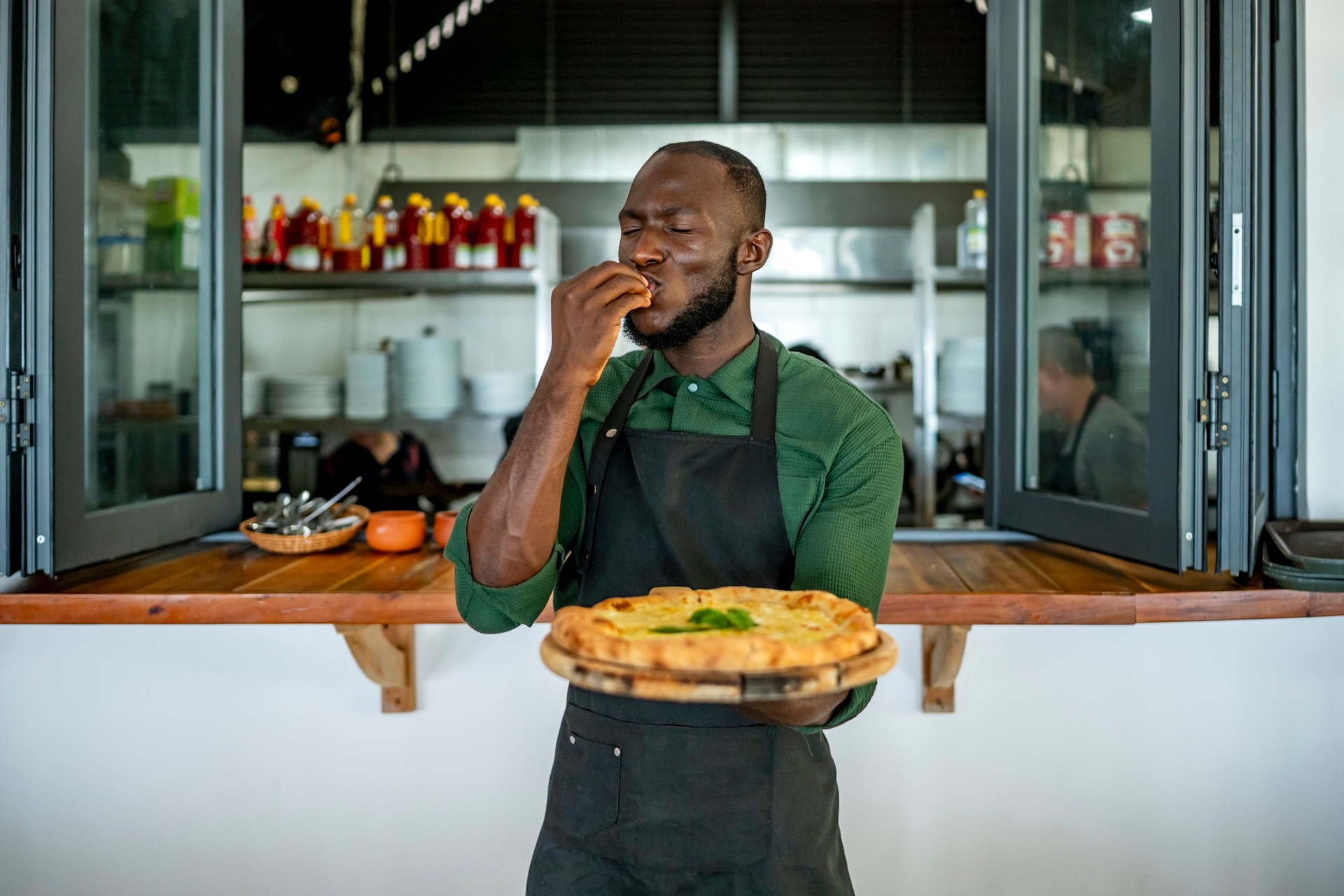Chef Tasting Freshly Baked Pizza in a Cozy Kitchen